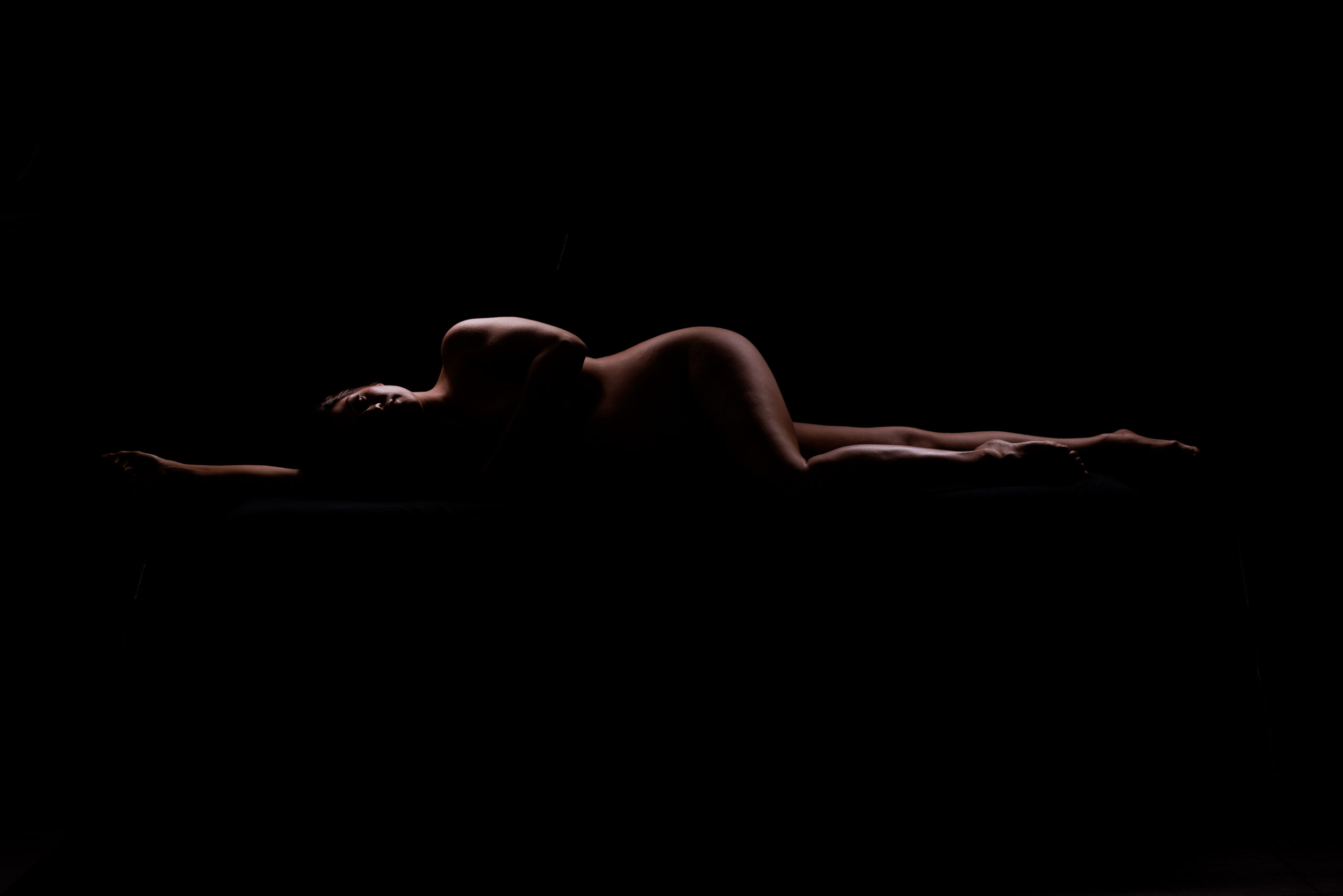 boudoir maternity reclining pose with silhouette lighting