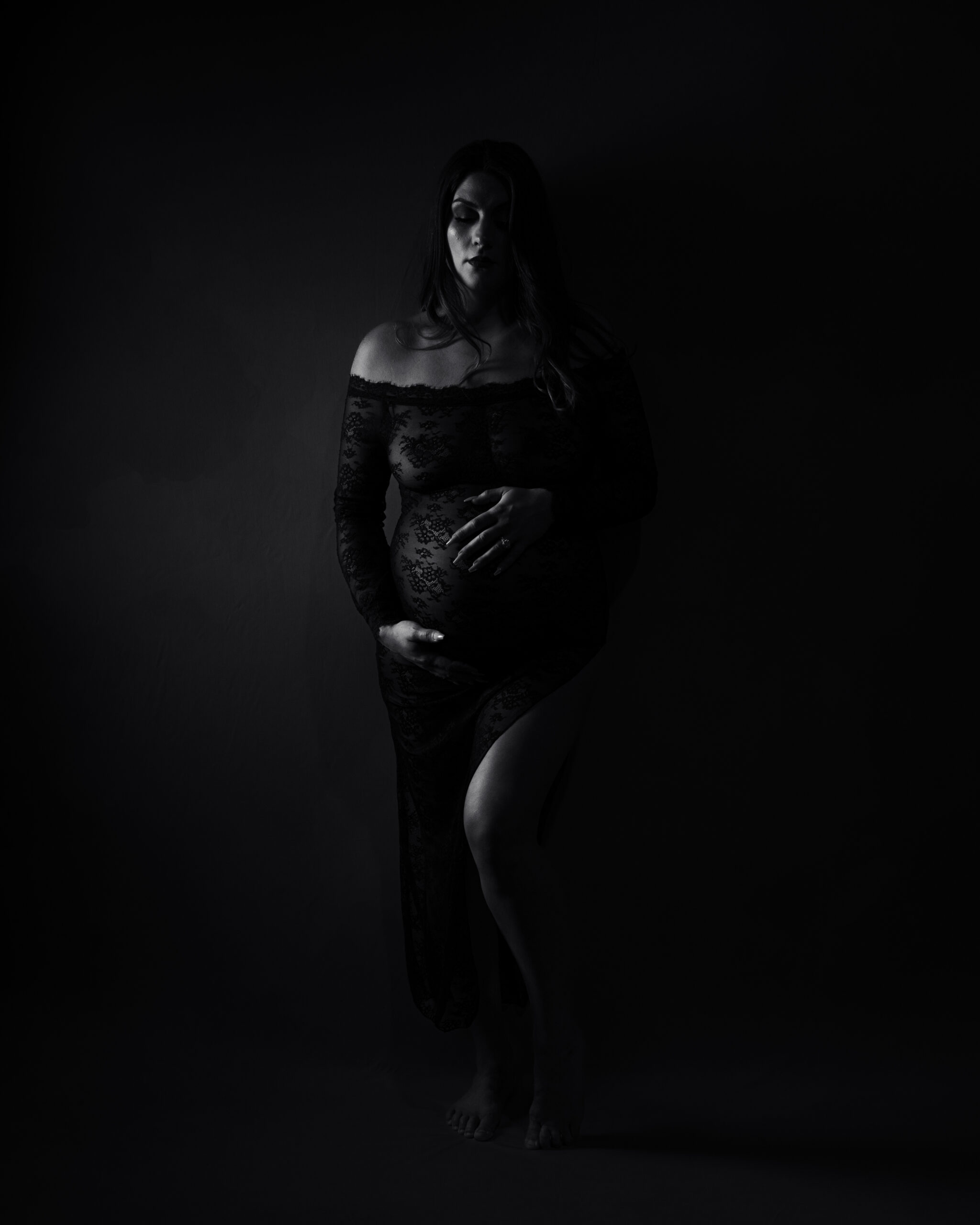 Elegant motherhood session with lace dress and soft shadows