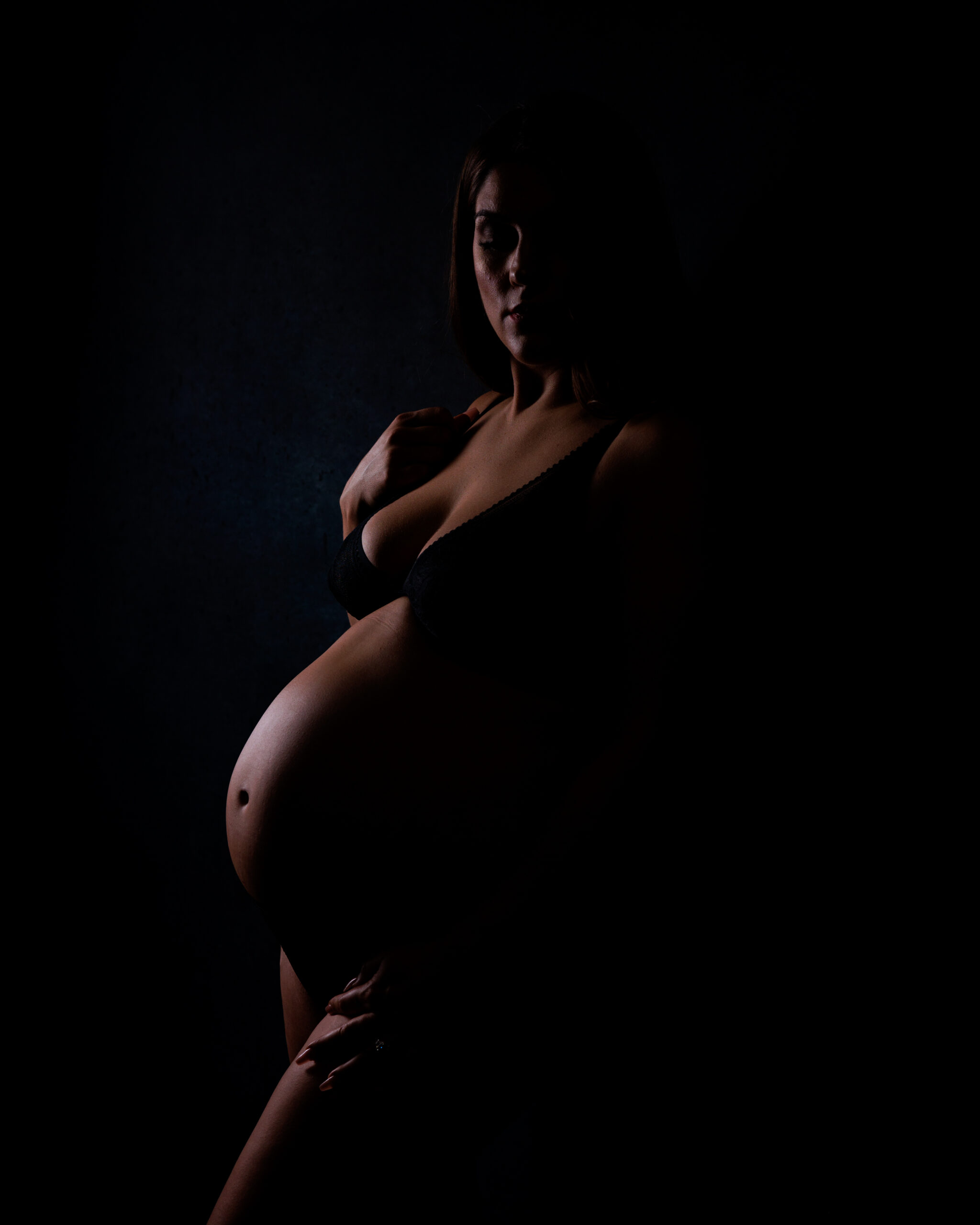 silhouette portrait of pregnant woman in dark studio lighting