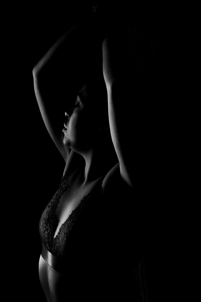black and white boudoir session portrait with arms raised and elegant silhouette