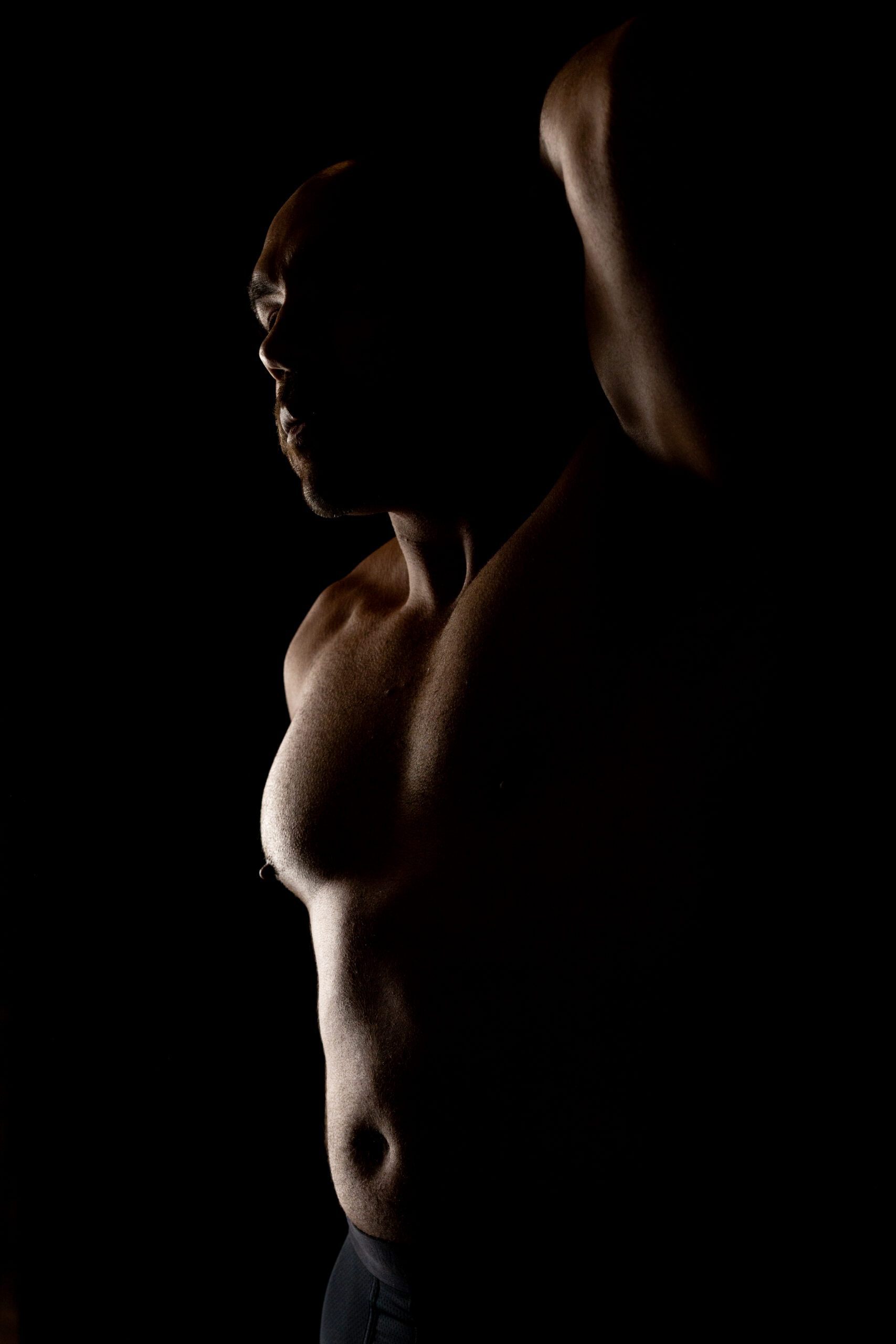 artistic male boudoir photography with shadow lighting and defined torso
