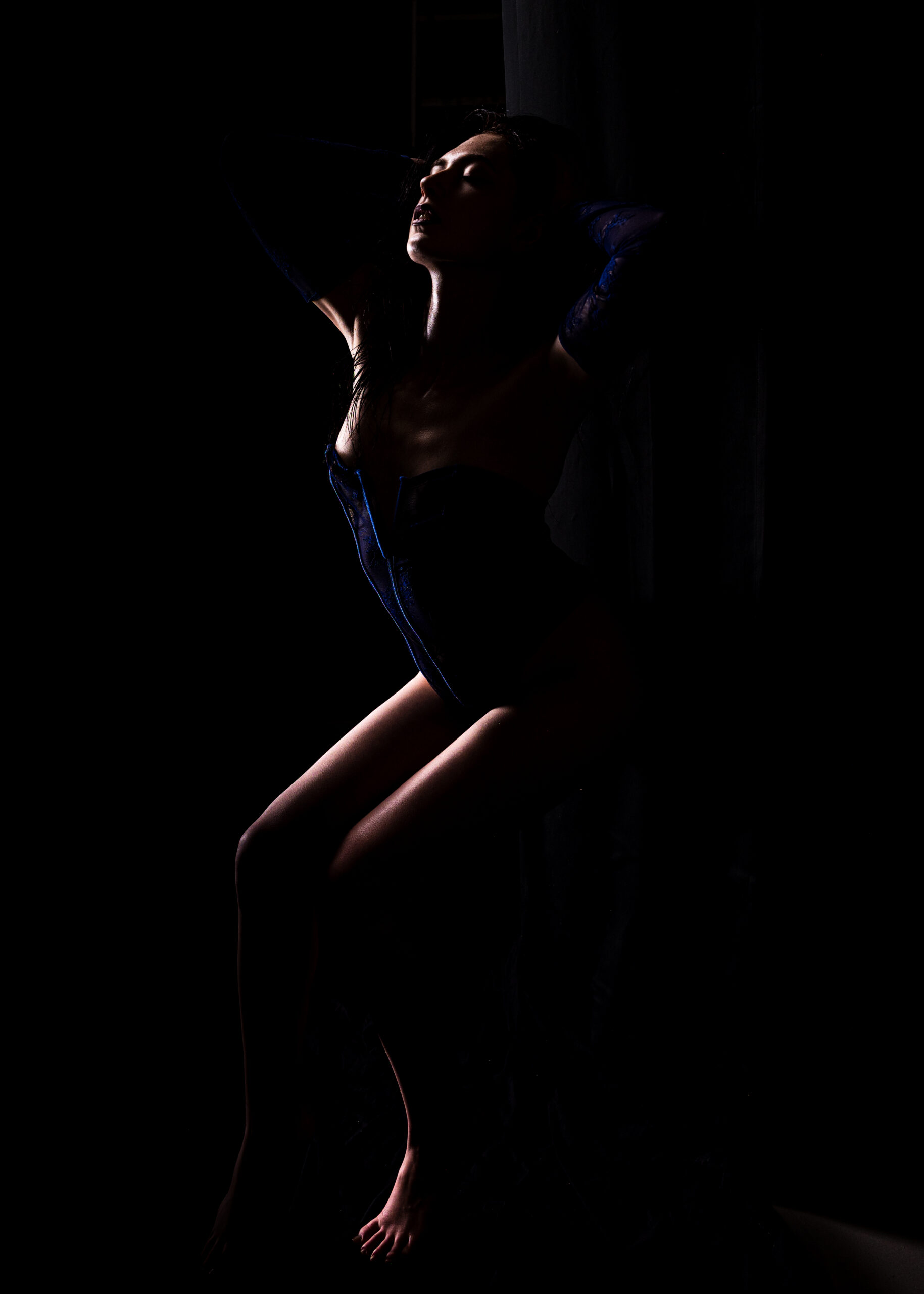 woman in blue corset with dramatic low lighting at Embrace Studio