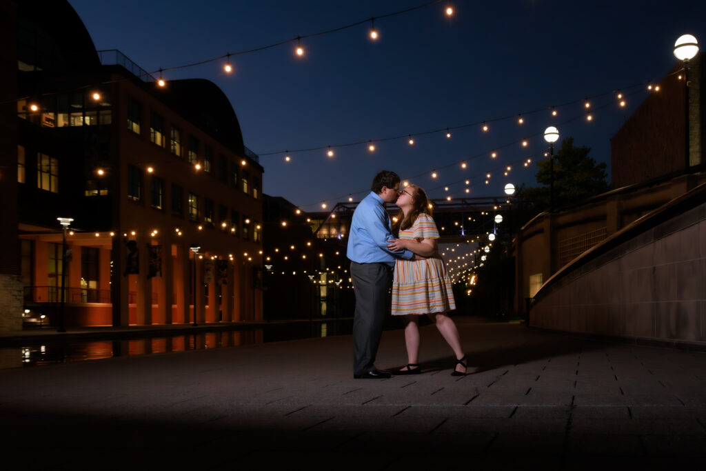 A couple kissing under lights on the indianapolis canal