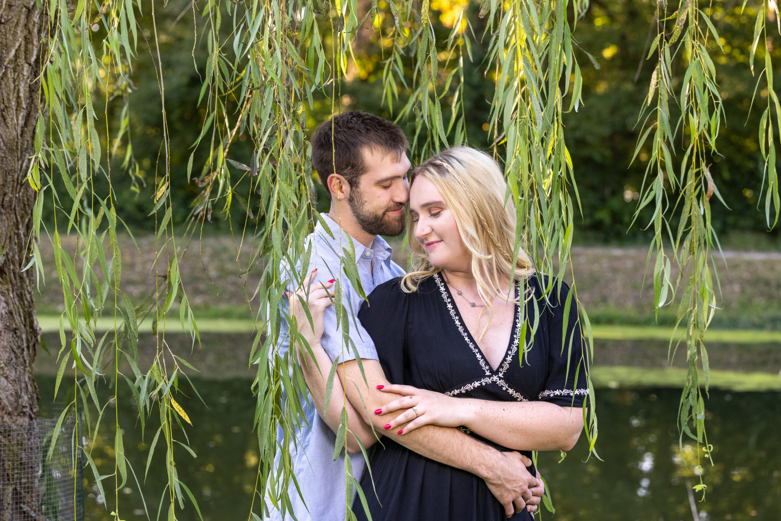 A couple standing under a willow tree at the holcomb gardens at butler university photographed by dimesnions photography Indianapolis family photographer