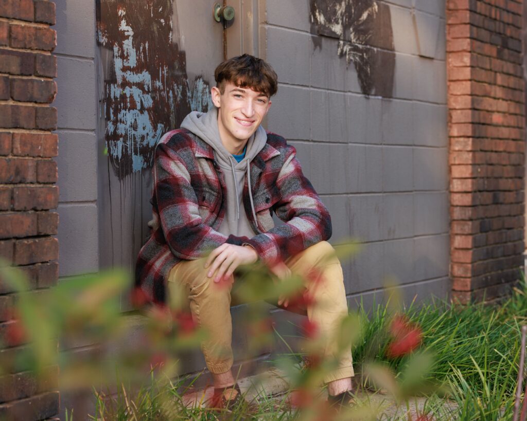 Indianapolis senior photo session featuring boy in flannel jacket against urban brick alley backdrop