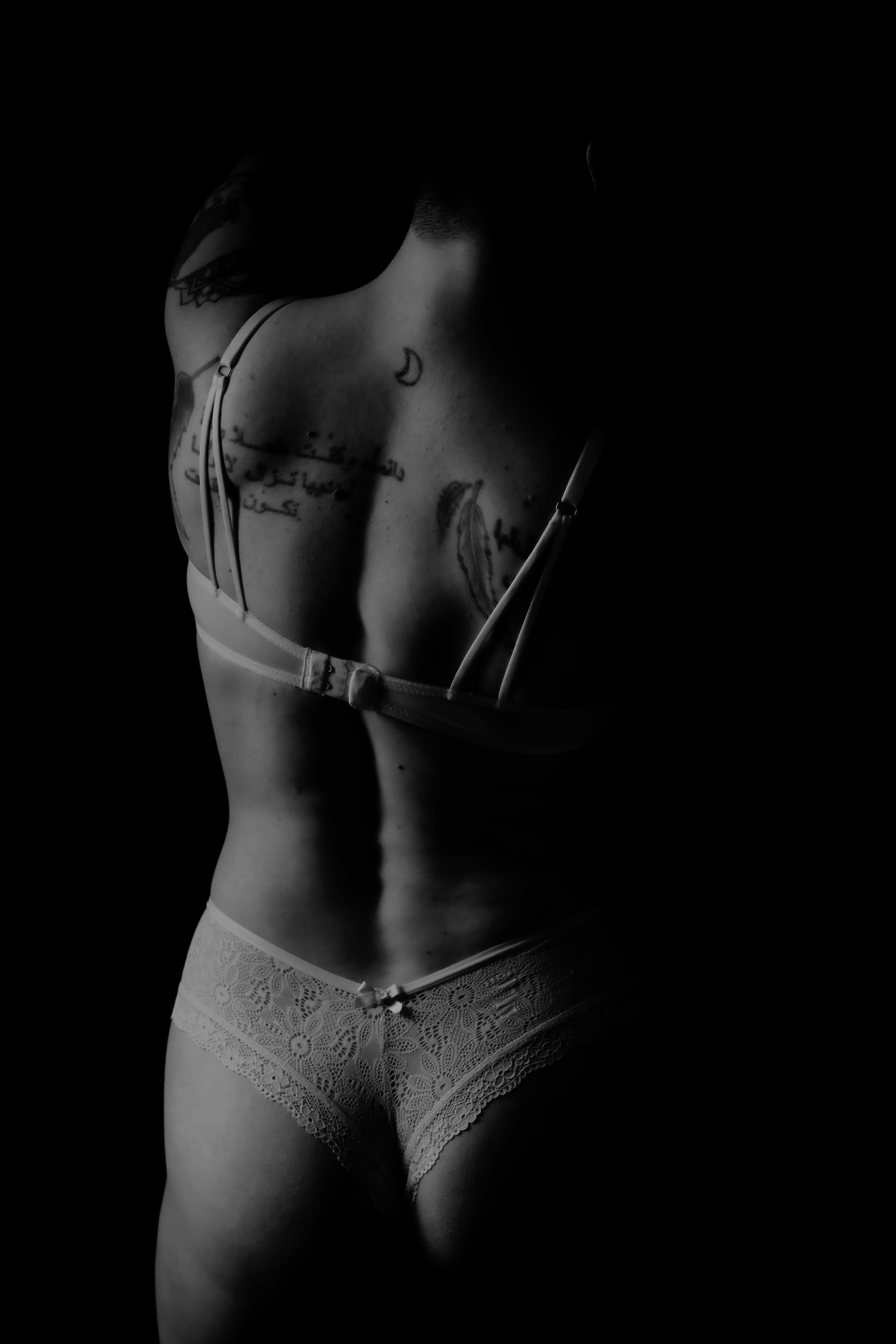 Woman's back showing her tattoos during a boudoir shoot