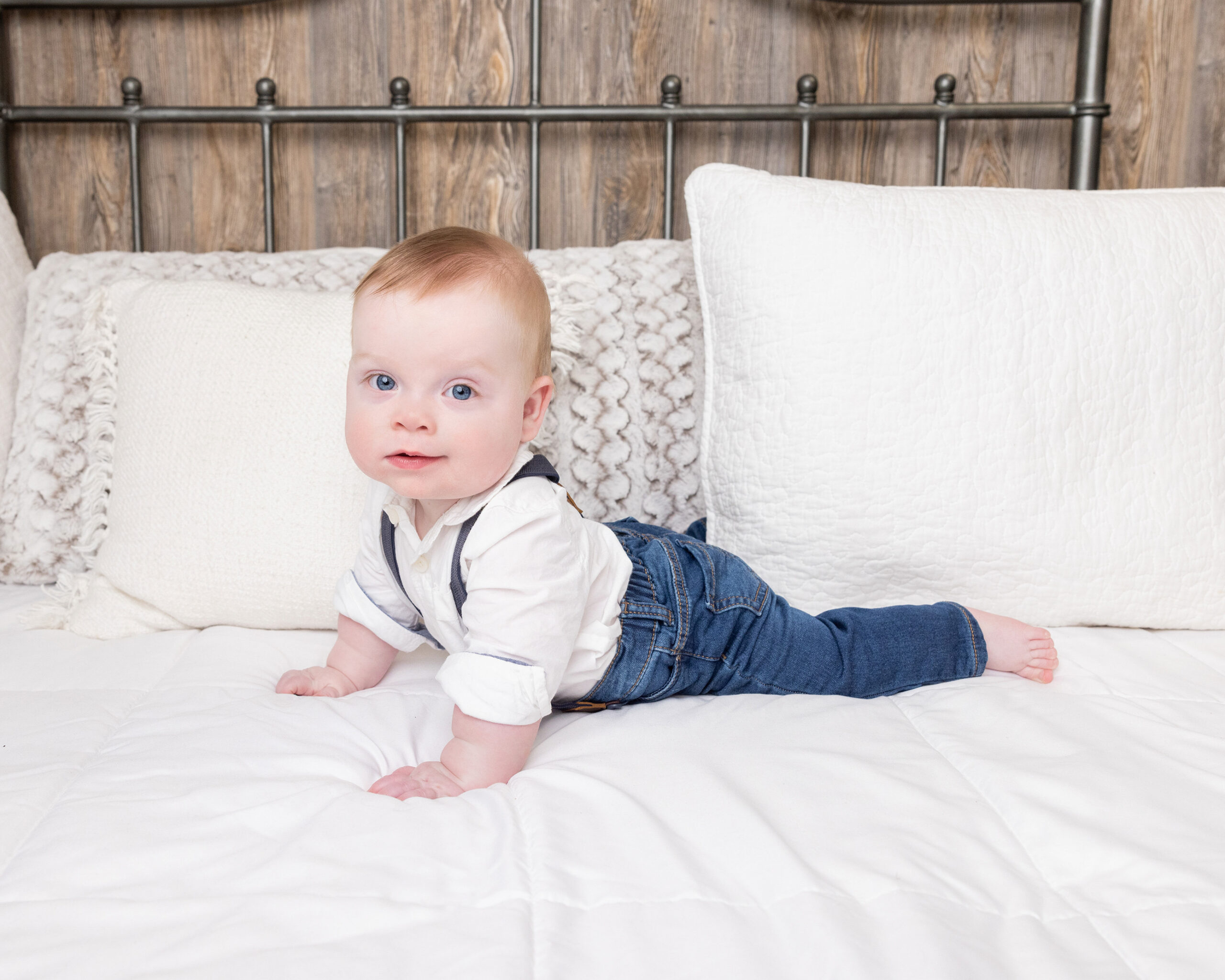 Baby boy crawling on white bed during a grow with me photography package sitter session