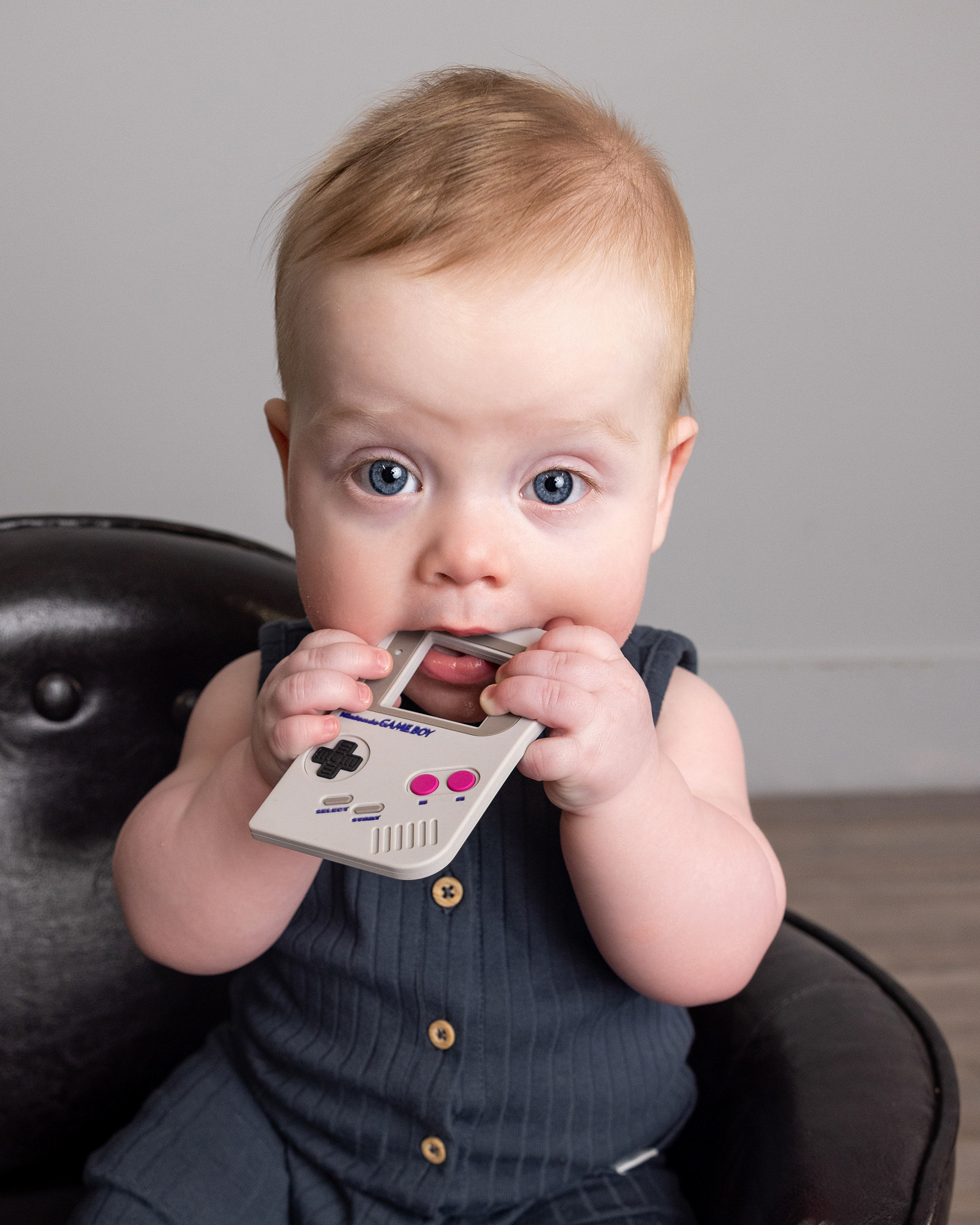 One year old chewing on toy during a grow with me photography package sitter session