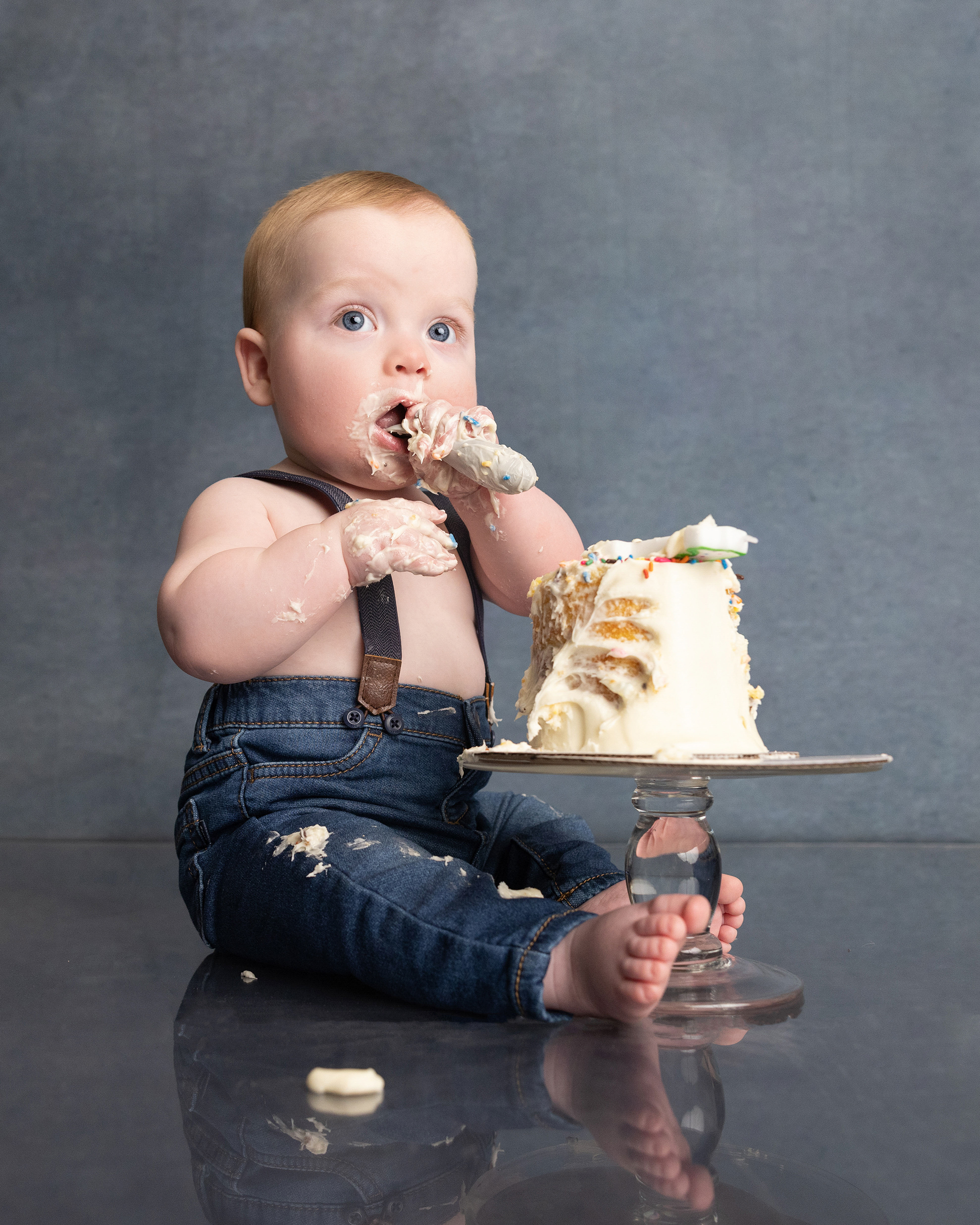 Baby eating birthday cake at the one year session of a grow with me photography package