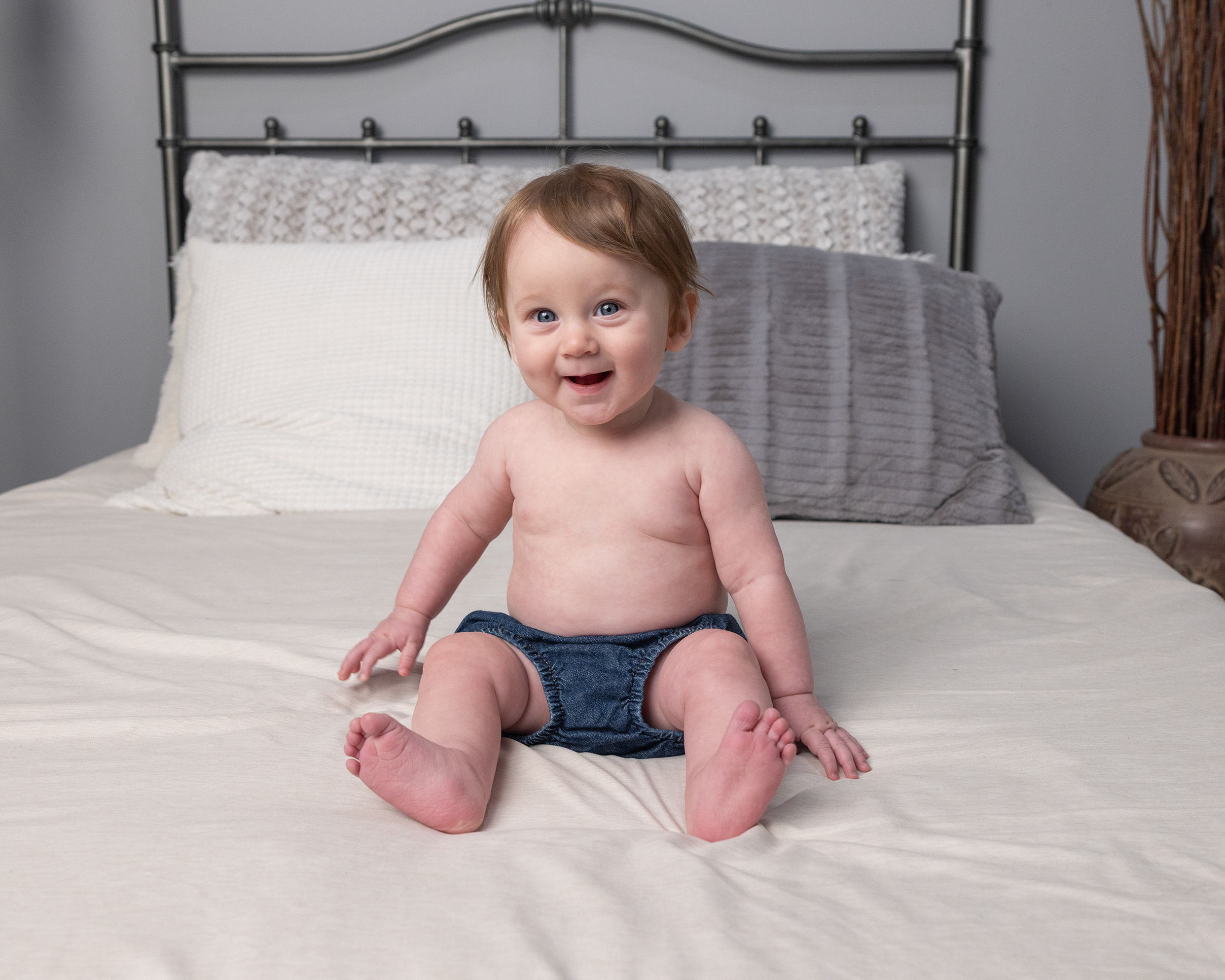 Baby smiling on bed during the sitter stage of a grow with me photography package