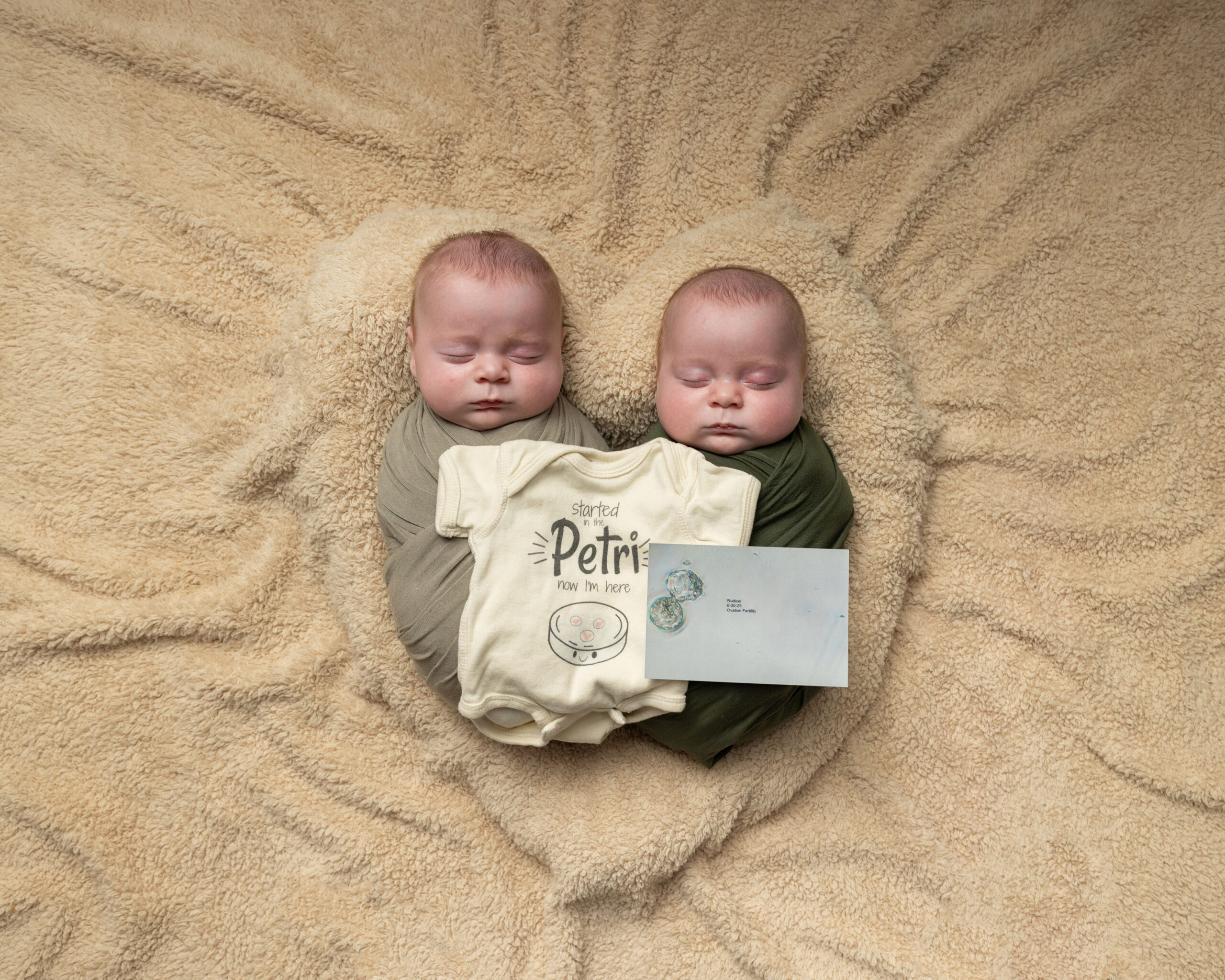 Twin newborns with onesie referencing their IVF journey