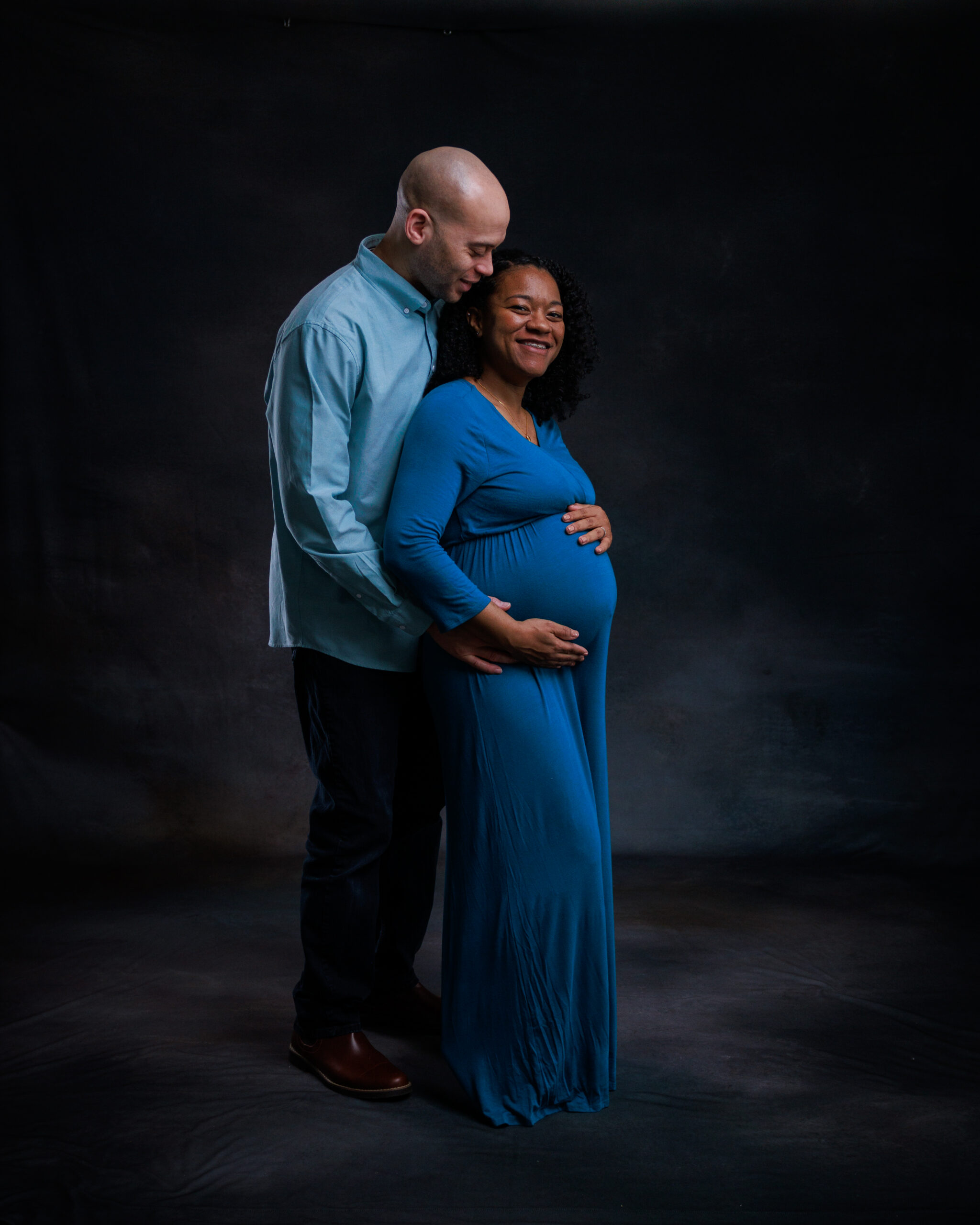 Couple posing in dark studio, grow with me photography package maternity portrait