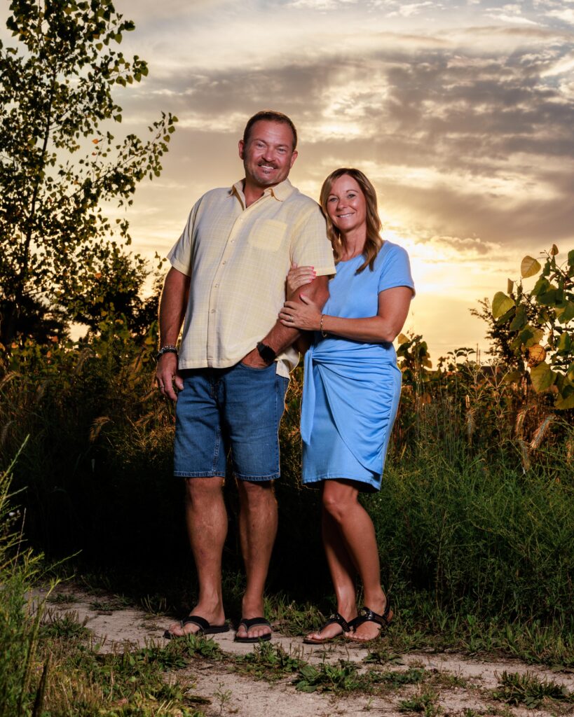 Couple smiling together in a golden field during a sunset family session