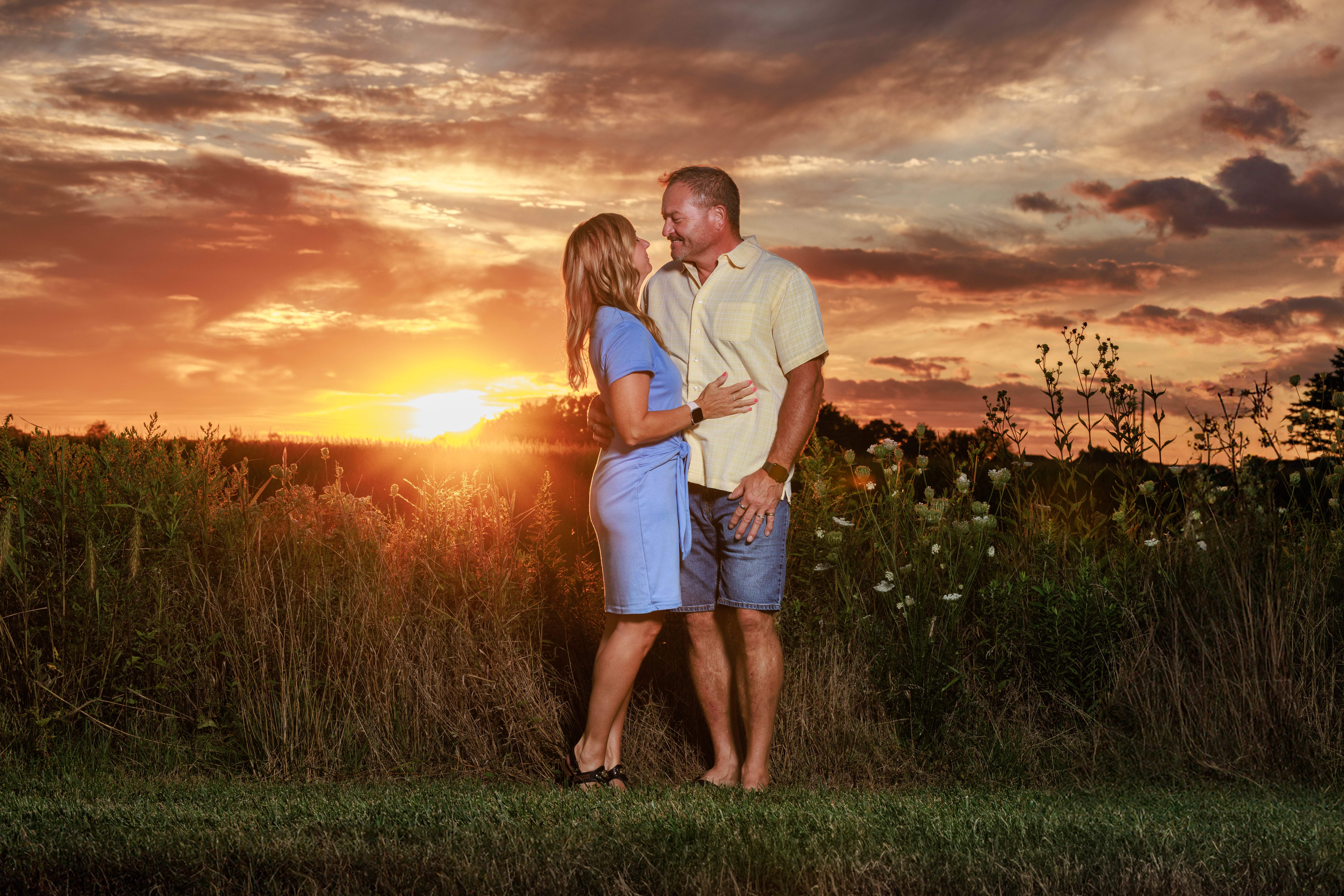 Couple standing face to face embracing in a field during golden hour sunset
