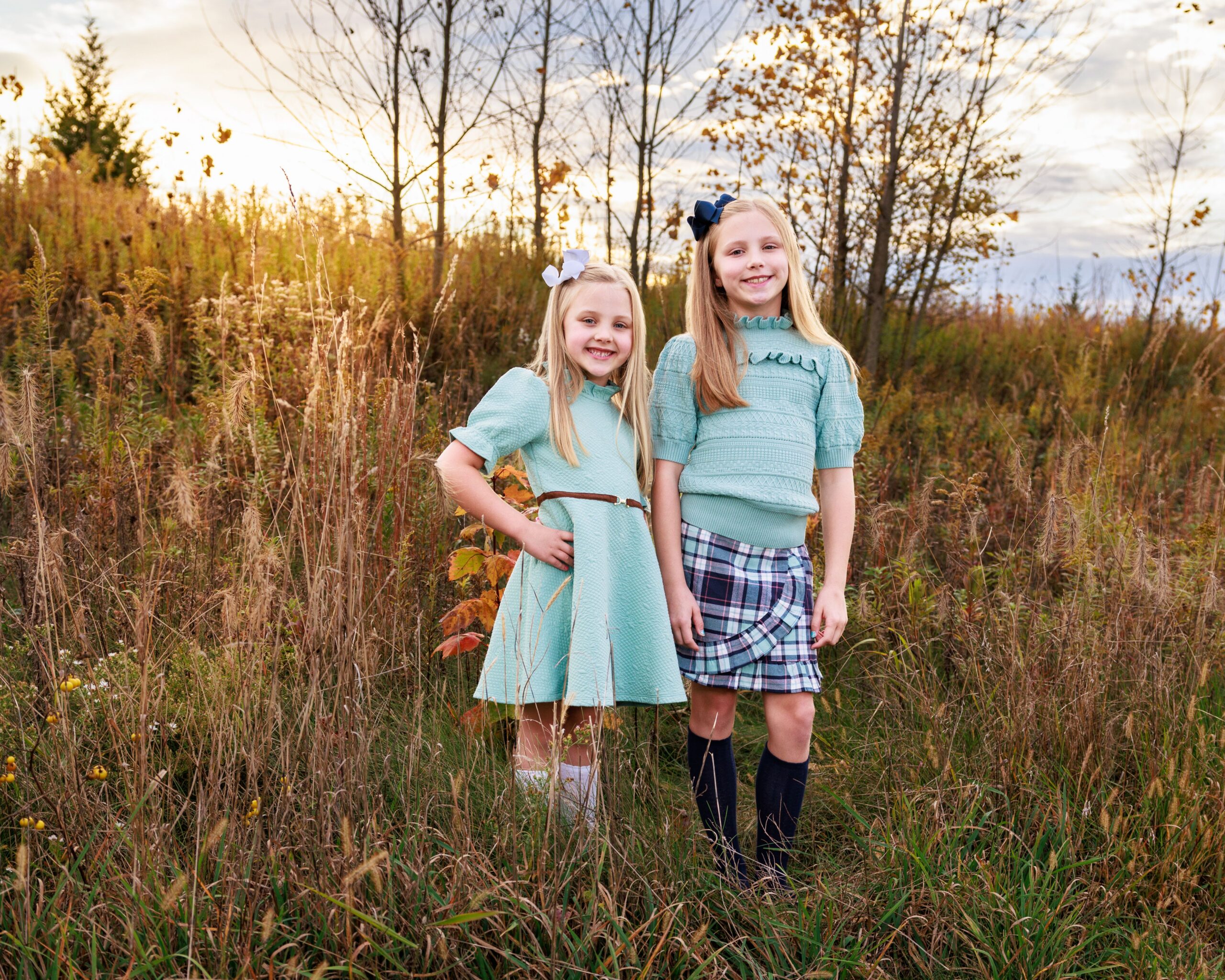 Two young sisters standing together among wildflowers during golden hour in Indianapolis