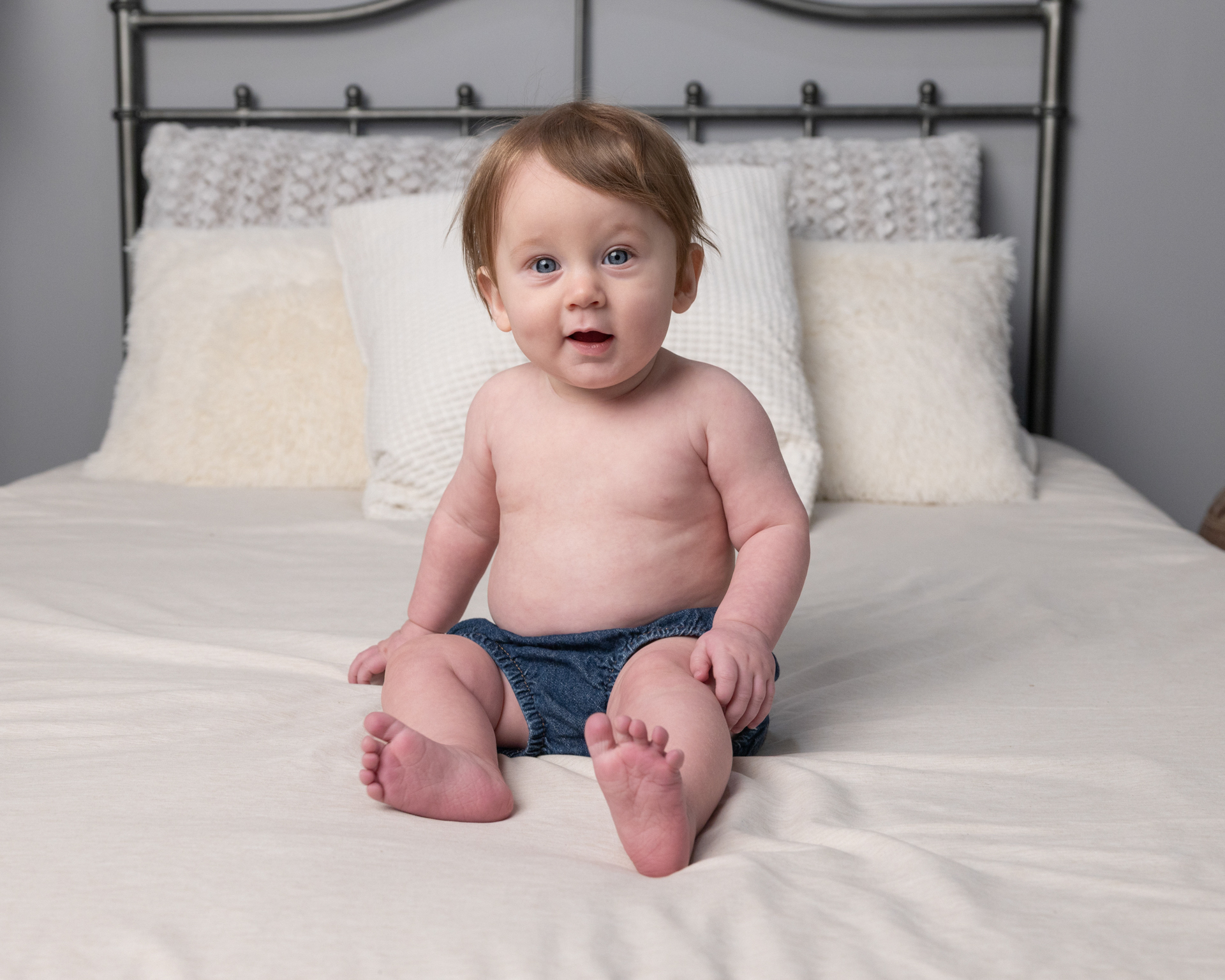 Baby boy smiling wide on a bed during a downtown Indianapolis sitter session