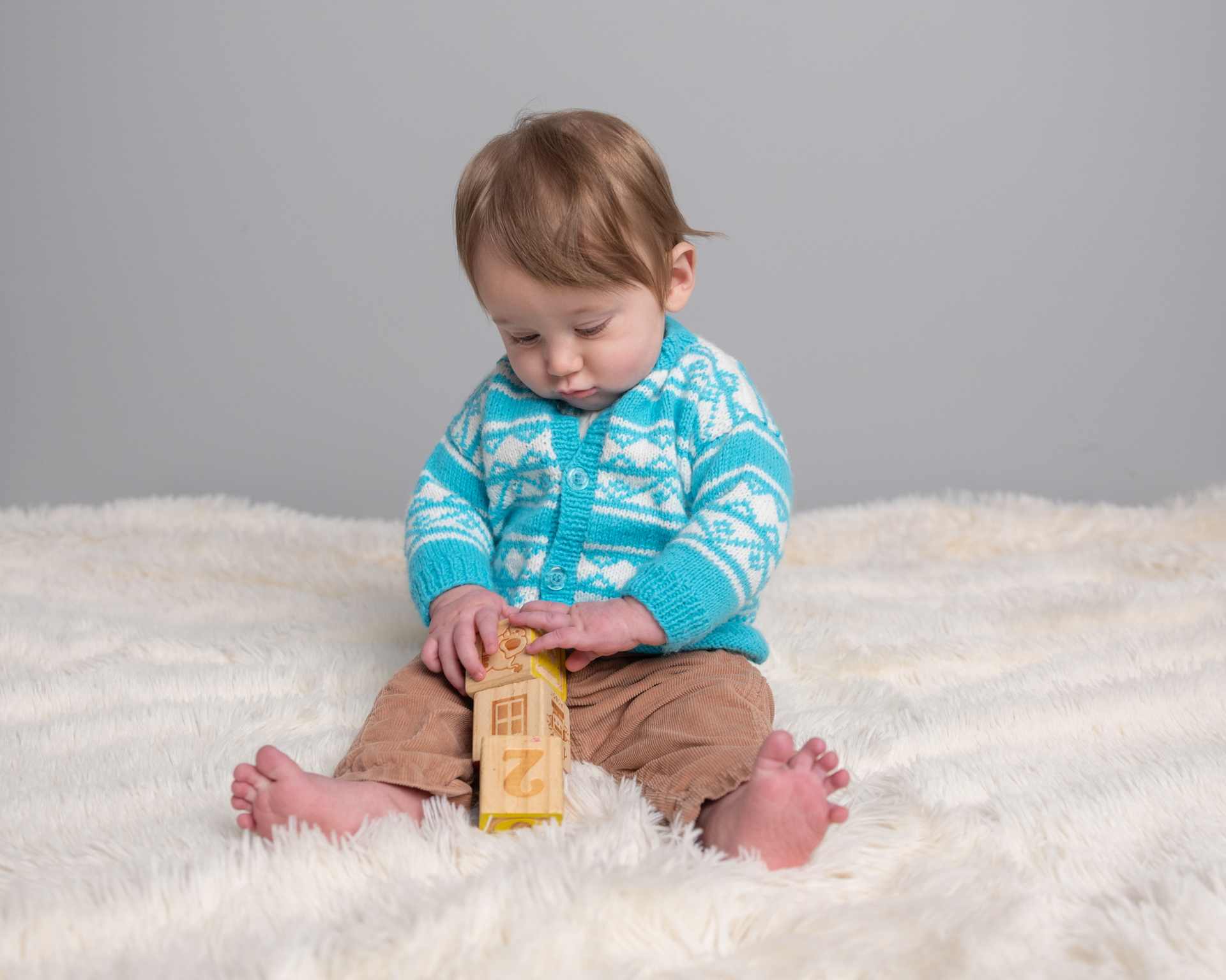 Baby boy playing with wooden alphabet blocks during his sitter session photography session