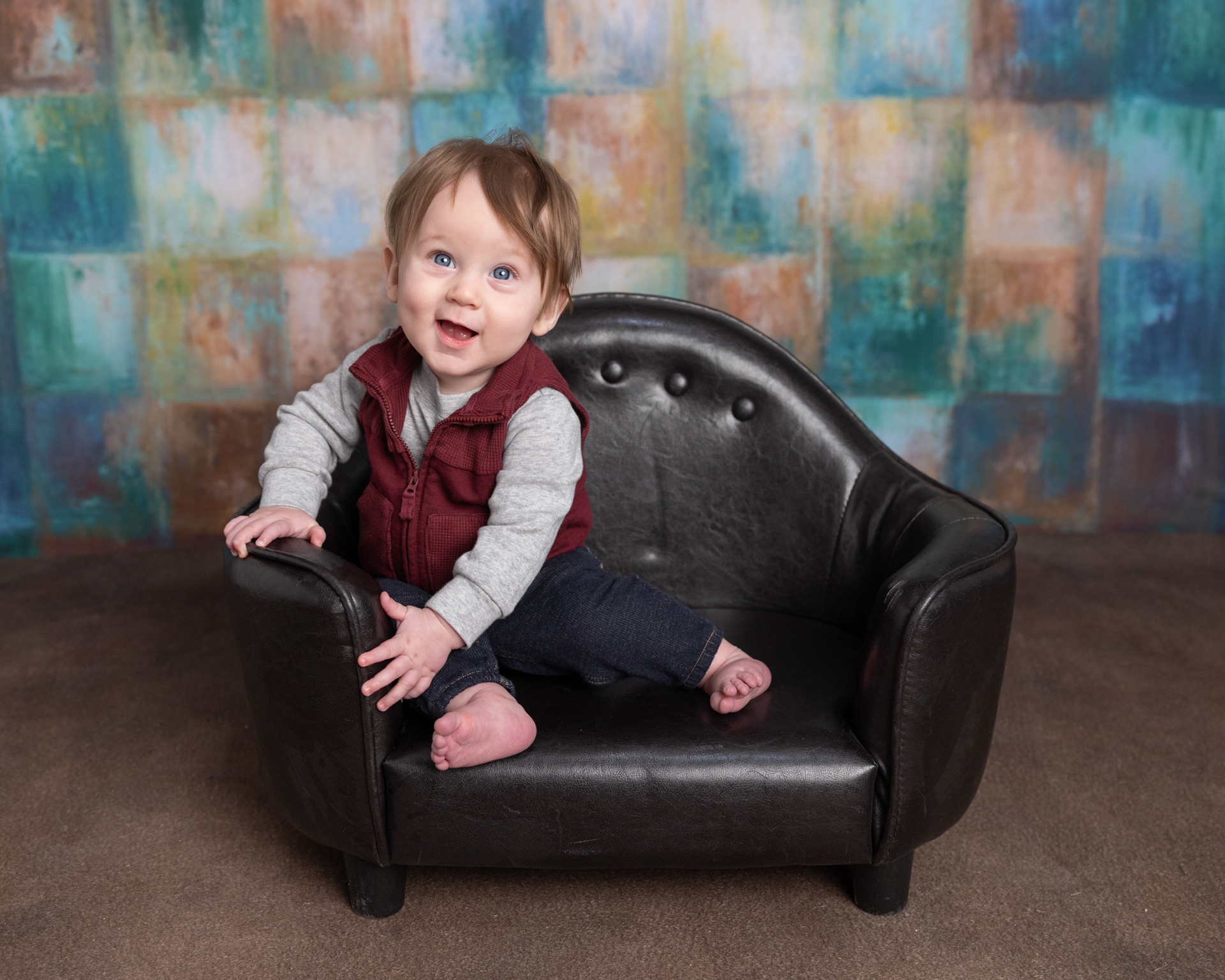 Close-up of baby boy grinning in a leather chair, sitter session photography detail shot