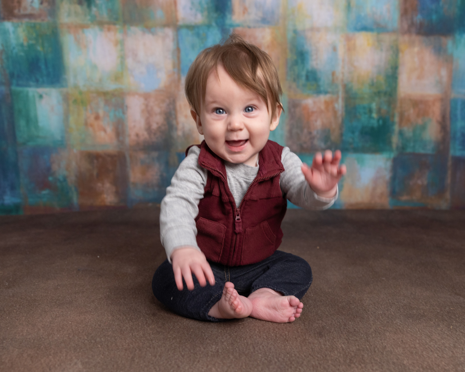 Baby boy laughing with a wide open smile on the floor, sitter session photography