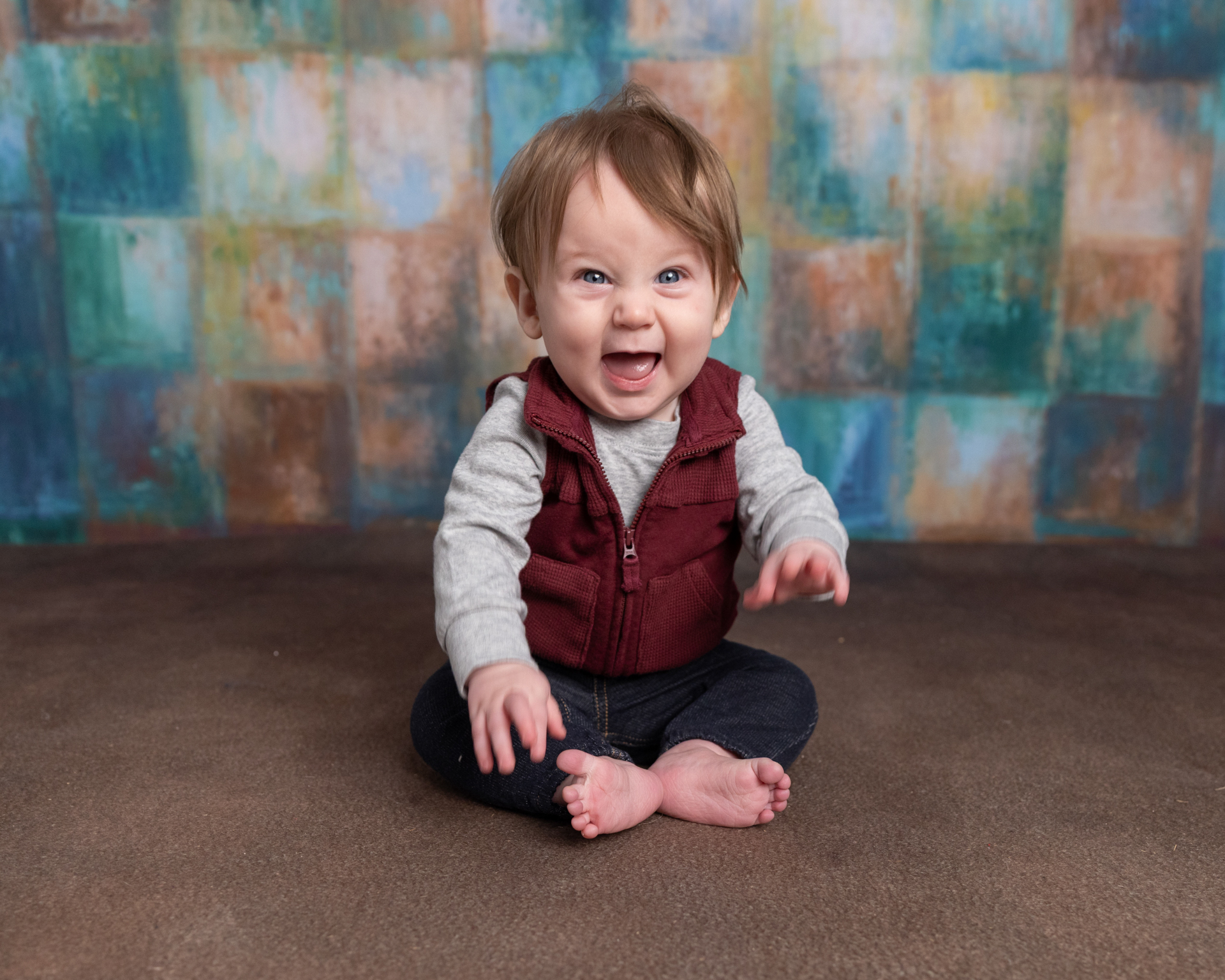 Baby boy sitting on the floor waving, sitter session photography candid moment