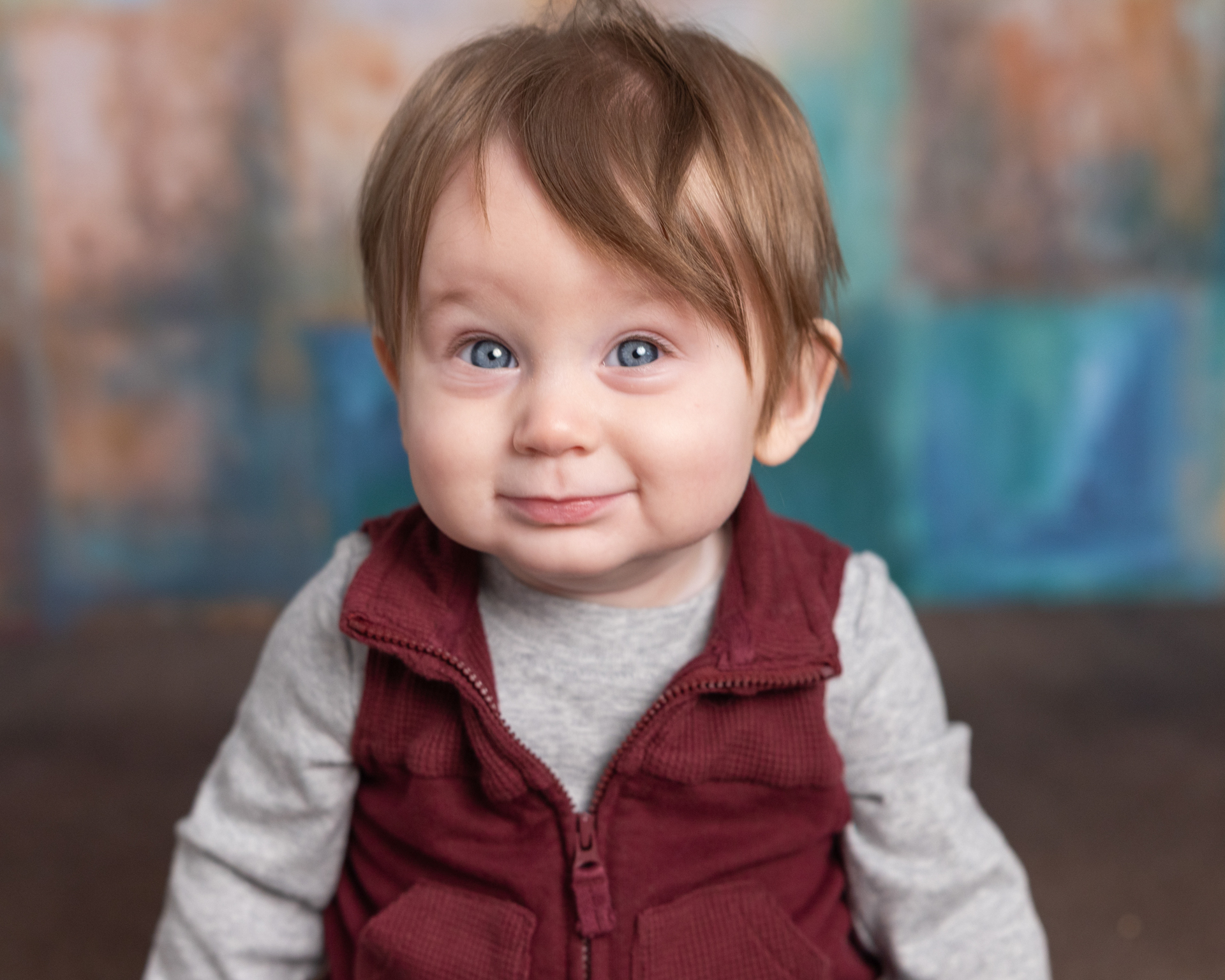 Close-up of baby boy's soft smile against a blurred colorful backdrop