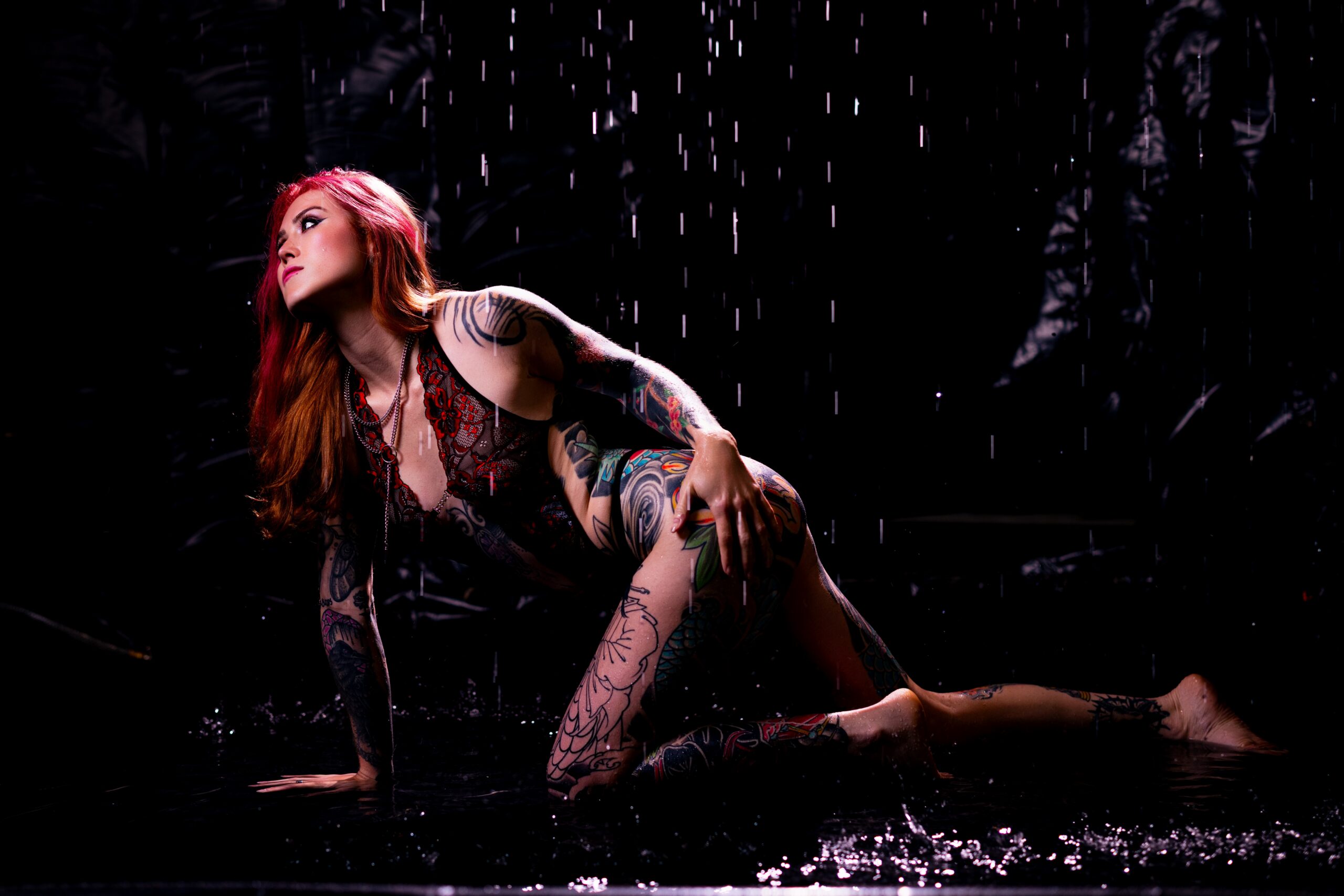 Deep red lighting and water droplets in the rain room boudoir experience at Embrace