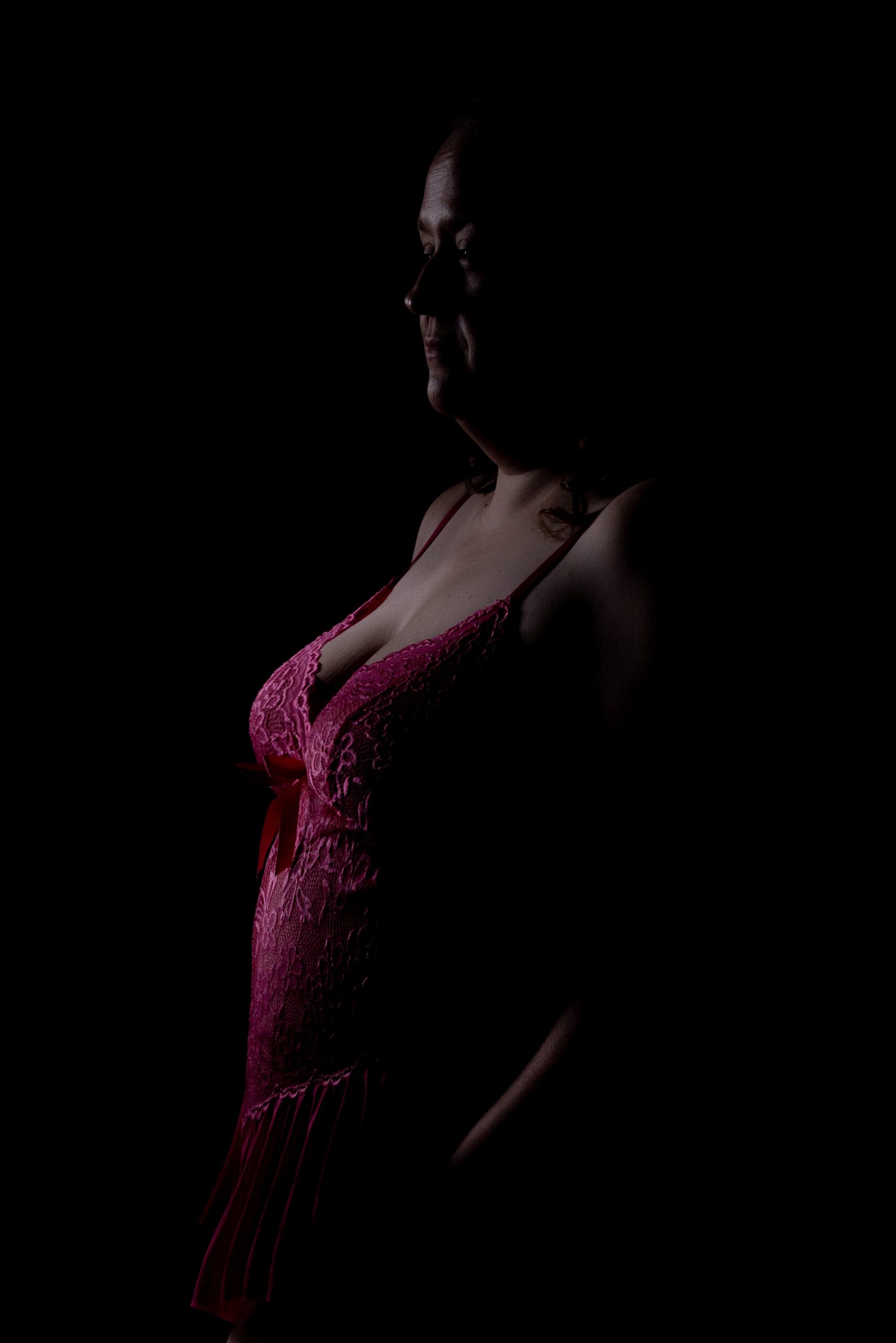 Magenta light traces a quiet silhouette against a dark studio background
