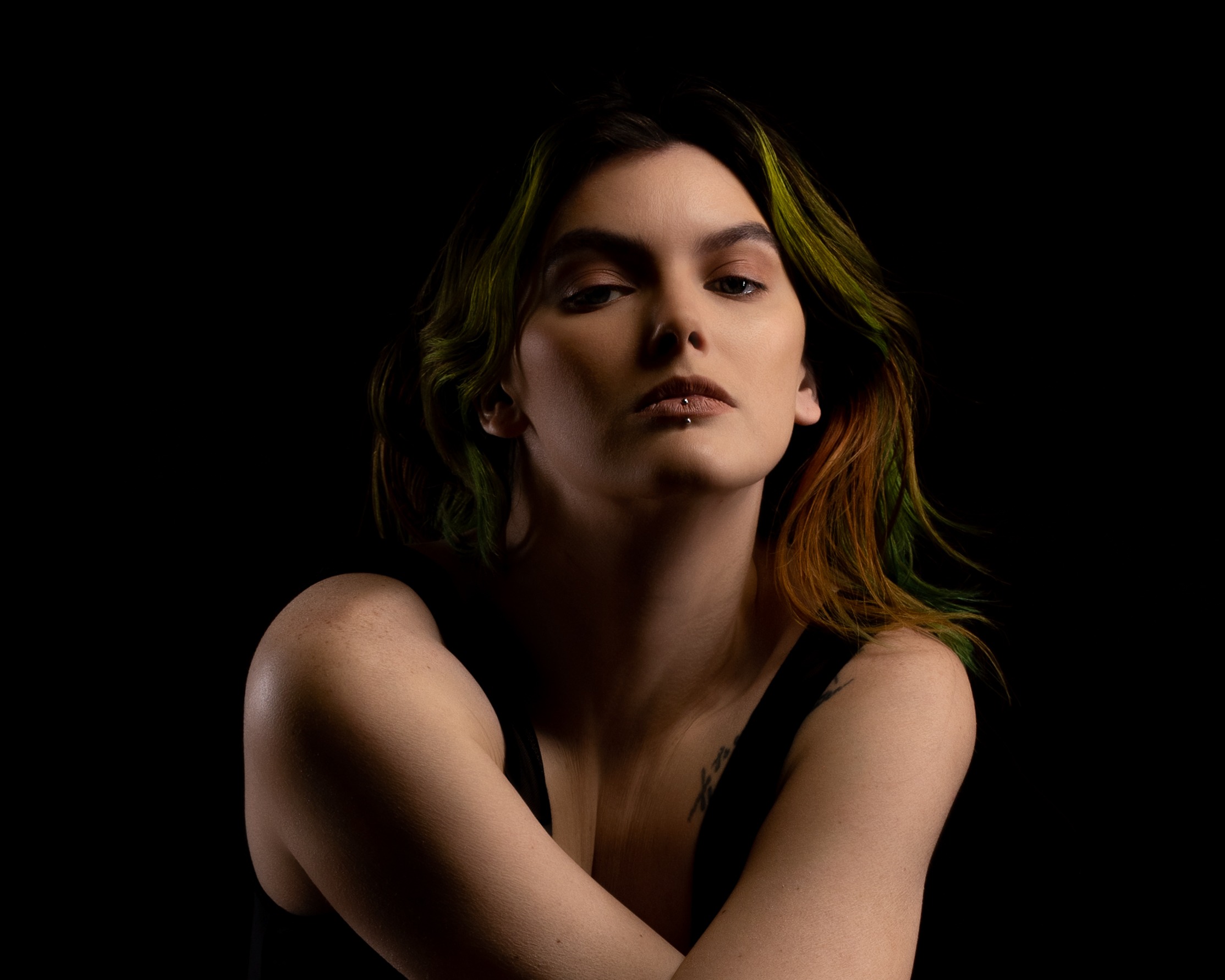 Deep shadow and warm directional light shape a close studio portrait against a dark backdrop
