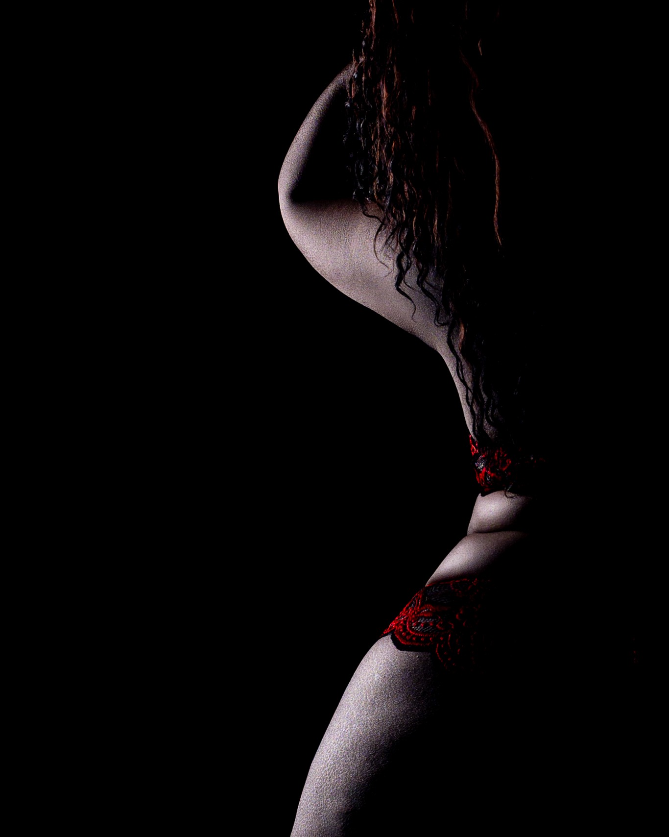 Vertical silhouette lighting against black creates a striking, minimal boudoir photography frame